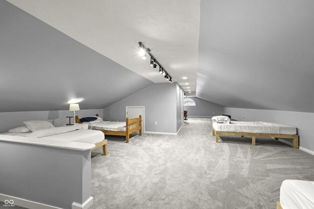 bedroom with baseboards, lofted ceiling, rail lighting, a textured ceiling, and carpet flooring