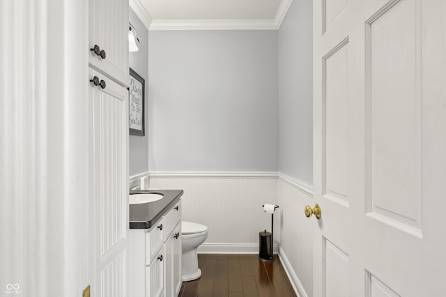 bathroom featuring crown molding, toilet, wood finished floors, and a wainscoted wall