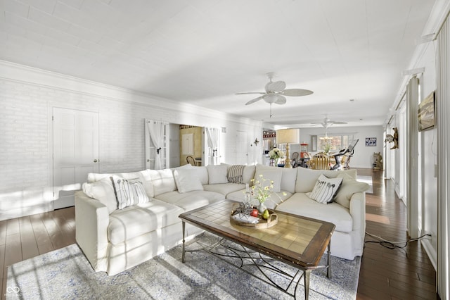 living area featuring brick wall, wood-type flooring, and ceiling fan