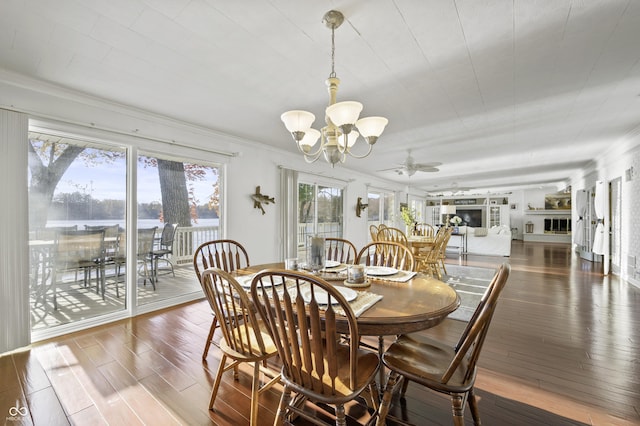 dining room featuring ceiling fan with notable chandelier, wood finished floors, and ornamental molding