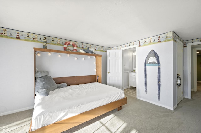 carpeted bedroom featuring ensuite bath and baseboards