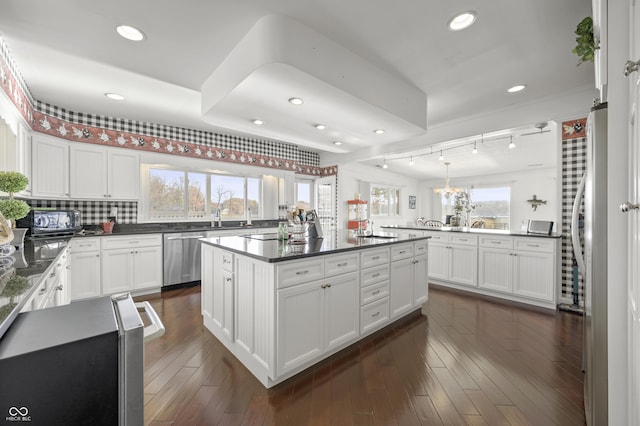 kitchen with plenty of natural light, dark countertops, appliances with stainless steel finishes, and dark wood finished floors