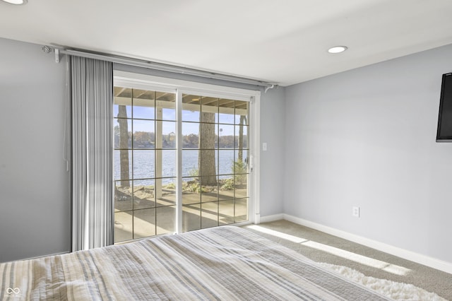 unfurnished bedroom featuring baseboards, carpet floors, recessed lighting, access to exterior, and a water view