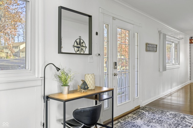 doorway to outside with plenty of natural light, wood finished floors, baseboards, and ornamental molding