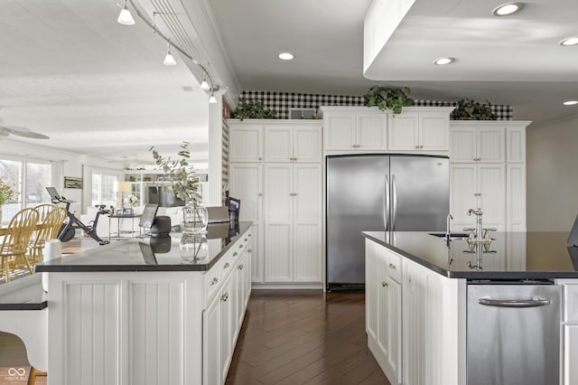 kitchen with white cabinetry, dark countertops, stainless steel fridge, and dark wood-style flooring