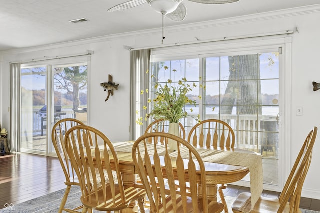 dining area with visible vents, a healthy amount of sunlight, wood finished floors, and crown molding