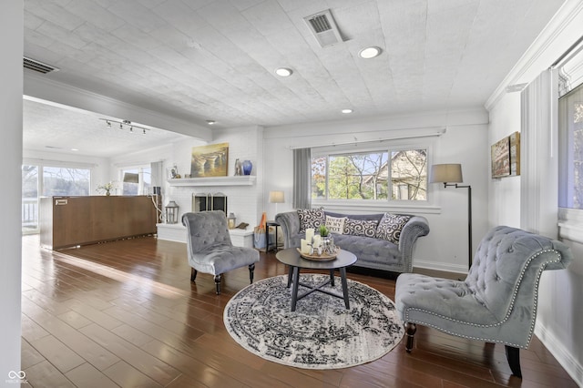 living area with baseboards, wood finished floors, visible vents, and ornamental molding