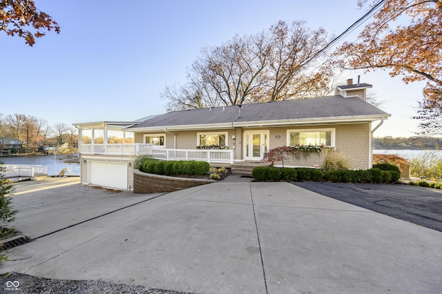 single story home featuring an attached garage, a water view, driveway, and a chimney