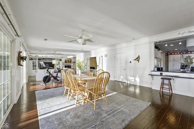 dining area with wood-type flooring, brick wall, ornamental molding, and a ceiling fan