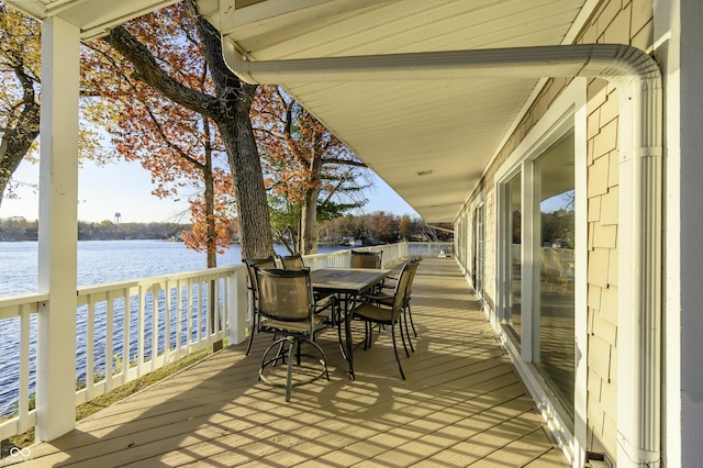 deck with outdoor dining space and a water view