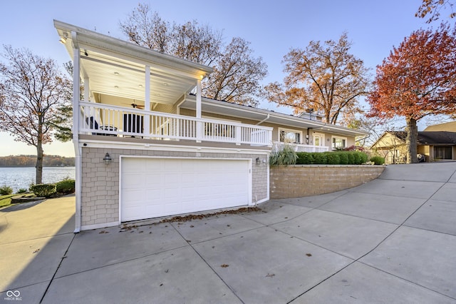 view of front of house with an attached garage, a water view, and driveway