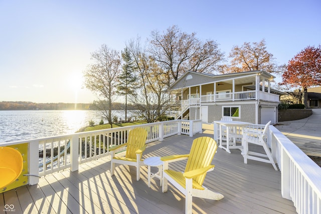 deck featuring stairway, a garage, and a water view