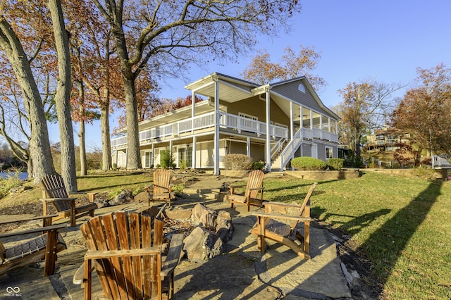 back of house featuring stairway, a fire pit, a lawn, and a patio area