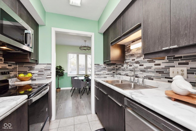 kitchen featuring dark brown cabinets, stainless steel appliances, light countertops, and a sink