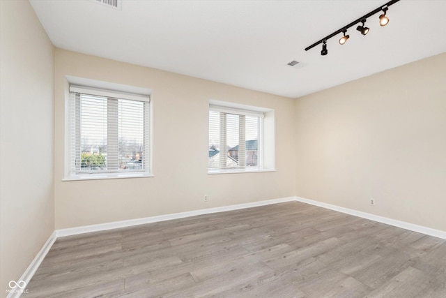 empty room featuring a wealth of natural light, baseboards, and wood finished floors