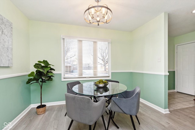 dining space with baseboards, an inviting chandelier, and wood finished floors