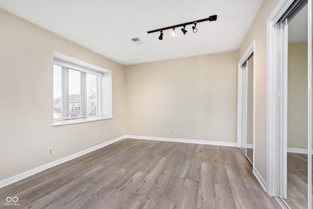 interior space featuring visible vents, track lighting, baseboards, wood finished floors, and a closet