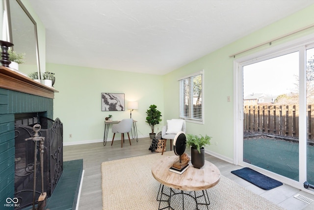 living area with visible vents, wood finished floors, a fireplace, and baseboards