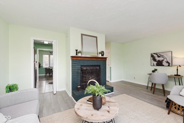 living area with a brick fireplace, baseboards, and wood finished floors