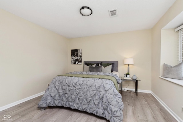 bedroom featuring visible vents, baseboards, and wood finished floors