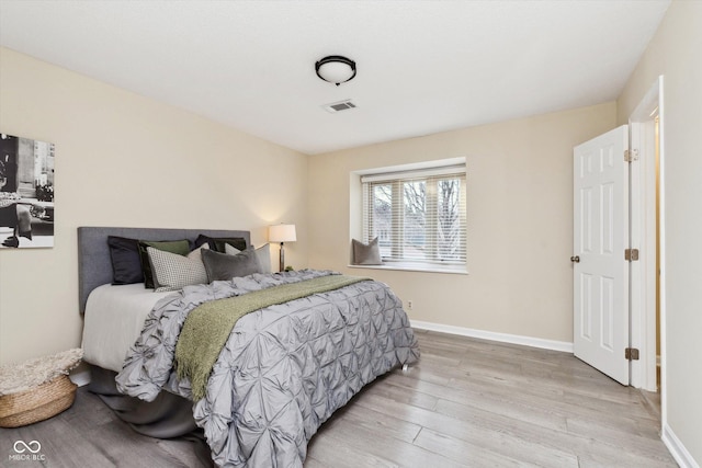 bedroom featuring visible vents, baseboards, and wood finished floors