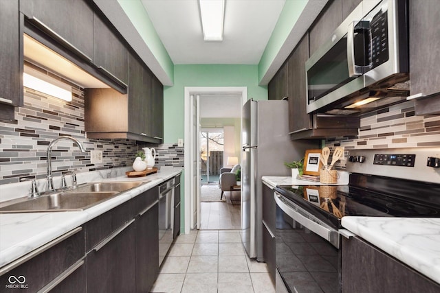 kitchen featuring dark brown cabinets, tasteful backsplash, appliances with stainless steel finishes, and a sink