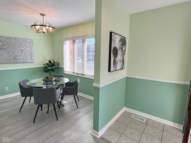 dining area featuring visible vents, baseboards, a notable chandelier, and a textured ceiling