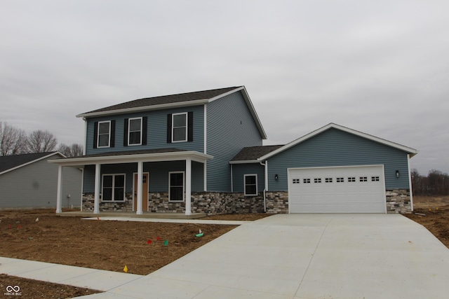 view of front facade featuring a porch, stone siding, a garage, and driveway