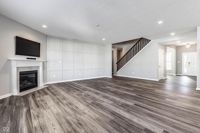 unfurnished living room featuring stairway, baseboards, dark wood finished floors, recessed lighting, and a fireplace