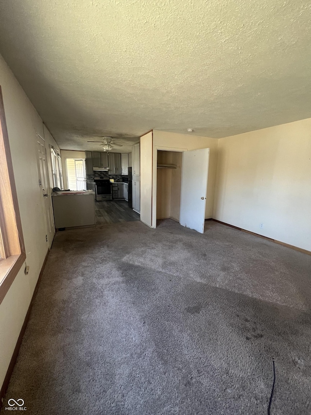 unfurnished living room with baseboards, dark carpet, a textured ceiling, and ceiling fan