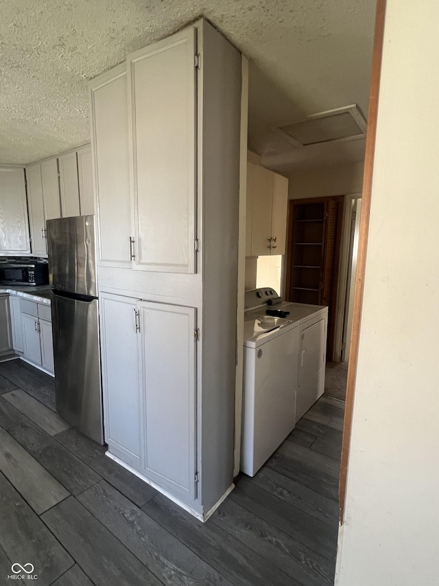 kitchen featuring washing machine and clothes dryer, black microwave, dark wood finished floors, freestanding refrigerator, and a textured ceiling