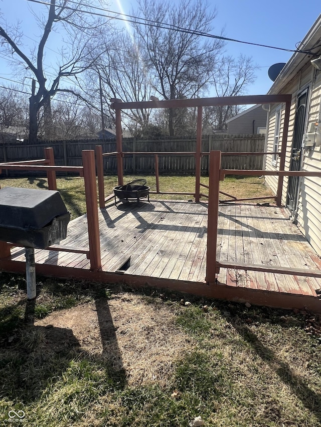 wooden deck featuring a lawn, a fenced backyard, and an outdoor fire pit