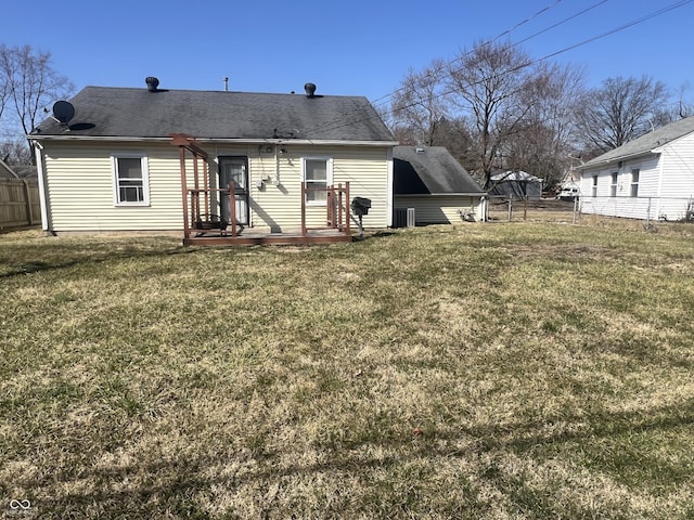 rear view of house with fence and a lawn