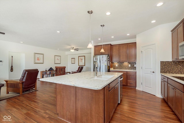 kitchen featuring open floor plan, stainless steel appliances, dark wood-type flooring, and a sink