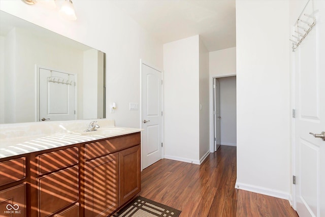 bathroom with vanity, wood finished floors, and baseboards