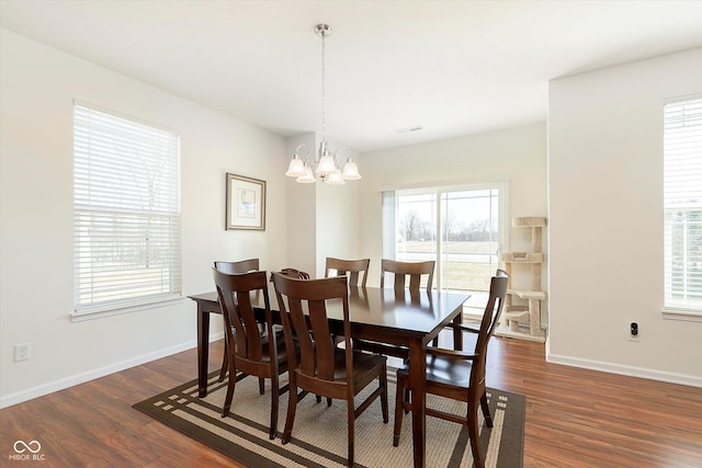 dining area with baseboards, a notable chandelier, and dark wood finished floors