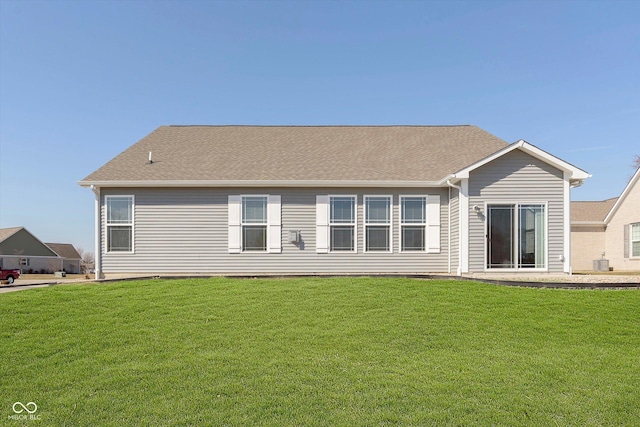 back of house featuring central AC unit, a lawn, and roof with shingles