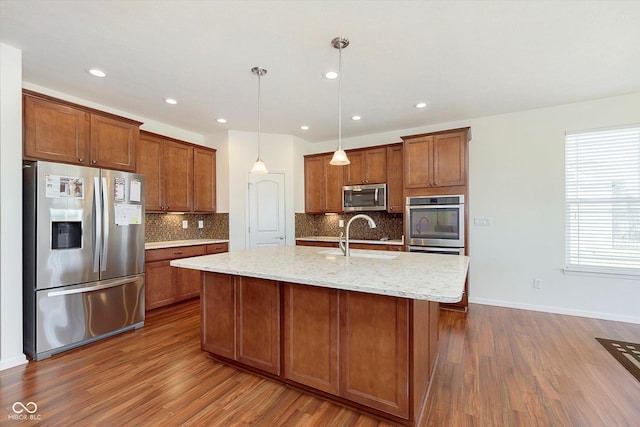 kitchen featuring brown cabinets, appliances with stainless steel finishes, dark wood-type flooring, and a sink