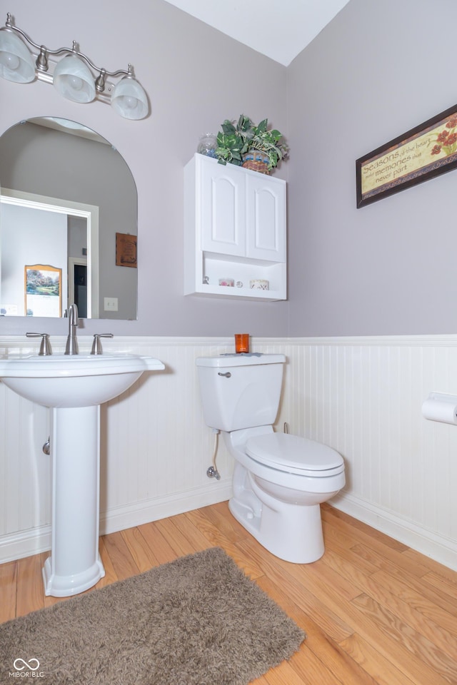 bathroom featuring a sink, a wainscoted wall, toilet, and wood finished floors