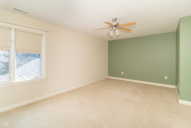 spare room featuring visible vents, light carpet, baseboards, and a ceiling fan