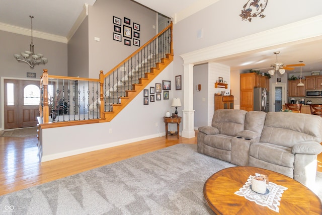 living room with stairway, a towering ceiling, light wood finished floors, and ornamental molding