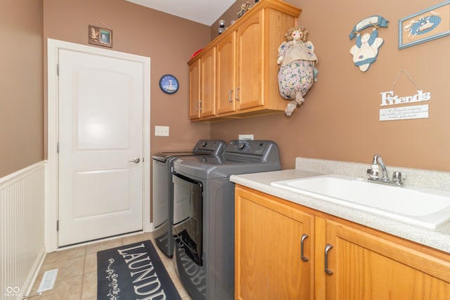 clothes washing area with a sink, cabinet space, separate washer and dryer, wainscoting, and light tile patterned floors