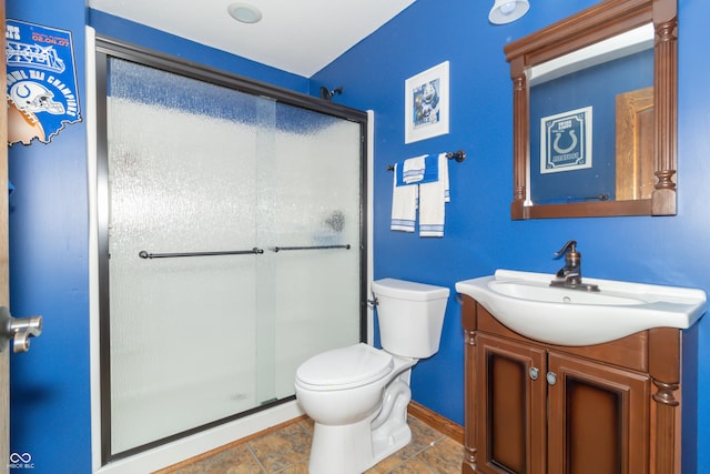 full bath featuring vanity, a shower stall, toilet, and baseboards