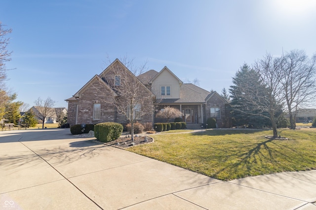 traditional-style house featuring a front lawn, brick siding, and driveway