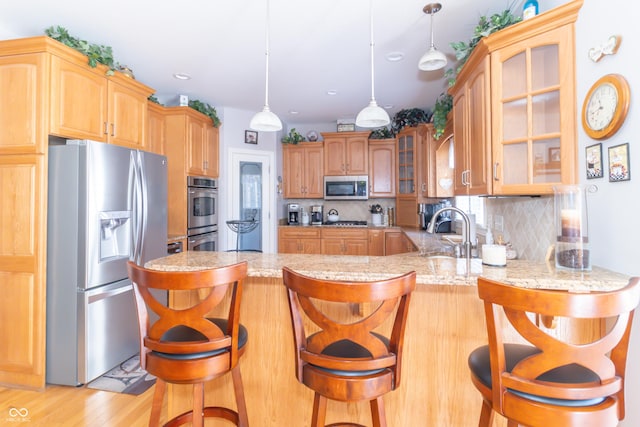 kitchen with tasteful backsplash, glass insert cabinets, a peninsula, stainless steel appliances, and a sink