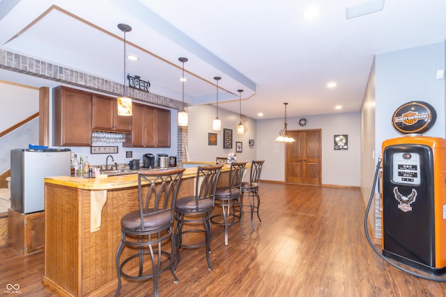 kitchen featuring pendant lighting, a breakfast bar, dark wood-type flooring, and light countertops