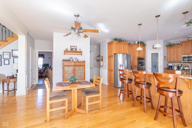 dining room with light wood-type flooring, ceiling fan, and stairs