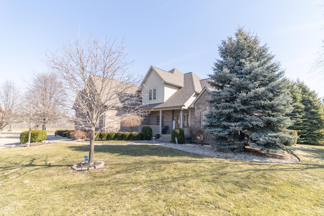 view of front of property featuring stone siding, a porch, a front yard, and a shingled roof