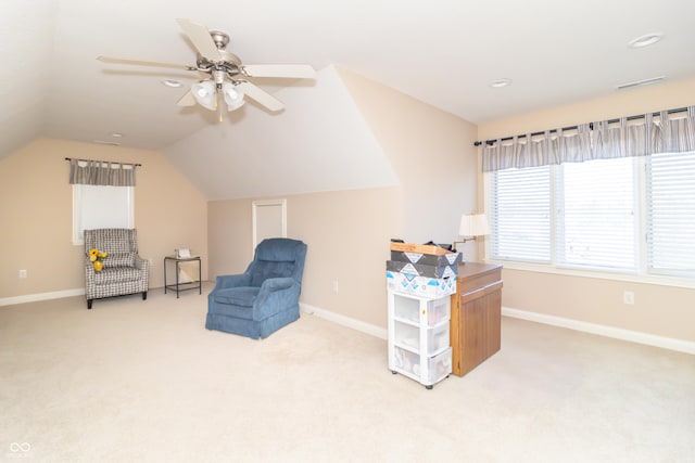 living area with a ceiling fan, lofted ceiling, light colored carpet, and baseboards