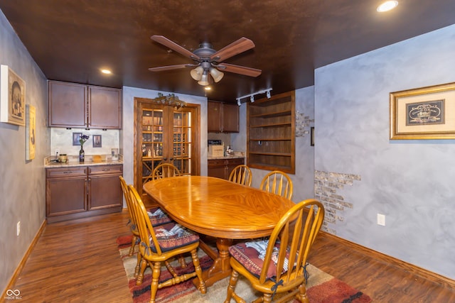 dining space with rail lighting, baseboards, a ceiling fan, and wood finished floors